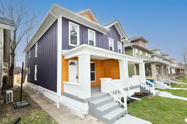 townhome / multi-family property featuring covered porch and a front yard