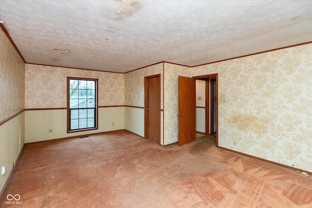 spare room with light carpet, crown molding, and a textured ceiling