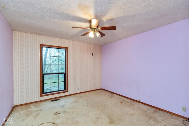 unfurnished room with a textured ceiling, light colored carpet, and ceiling fan