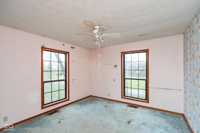 spare room featuring ceiling fan, light colored carpet, and a textured ceiling