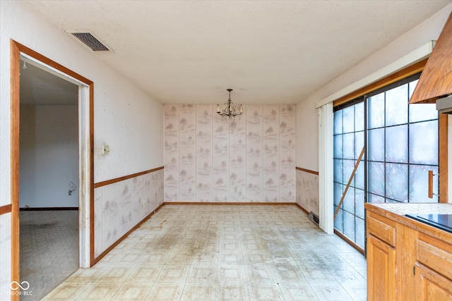 unfurnished dining area with a textured ceiling and a notable chandelier