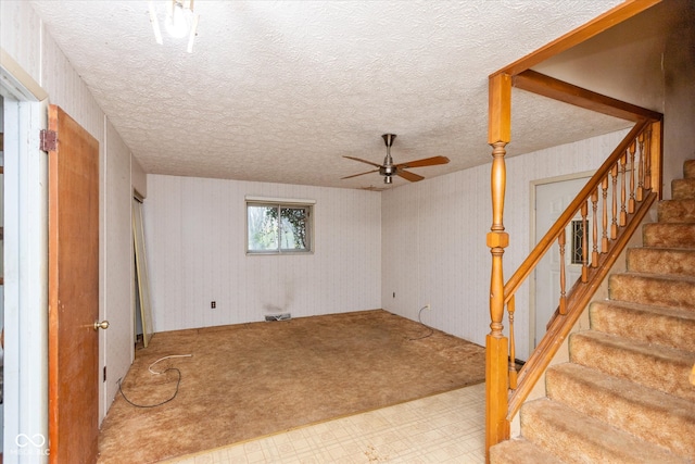 interior space featuring light carpet, ceiling fan, and a textured ceiling