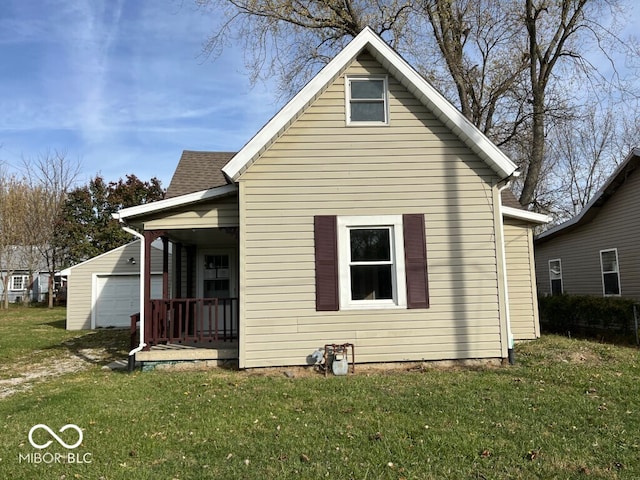 rear view of house featuring a garage, a lawn, and a porch