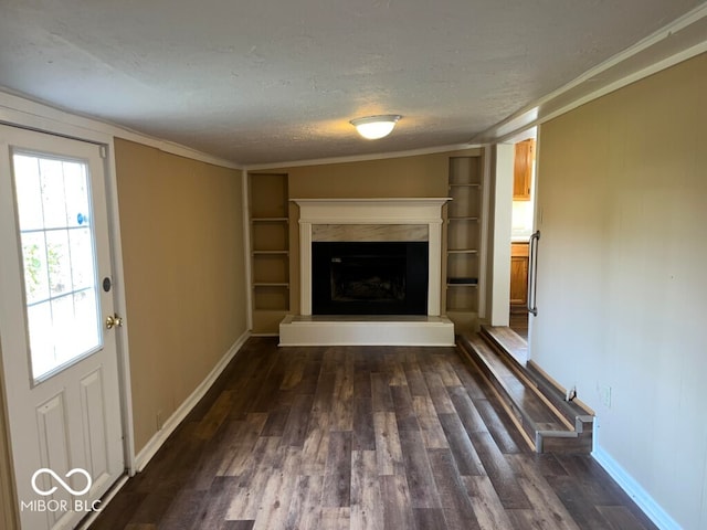 unfurnished living room with dark hardwood / wood-style flooring, lofted ceiling, built in shelves, and crown molding