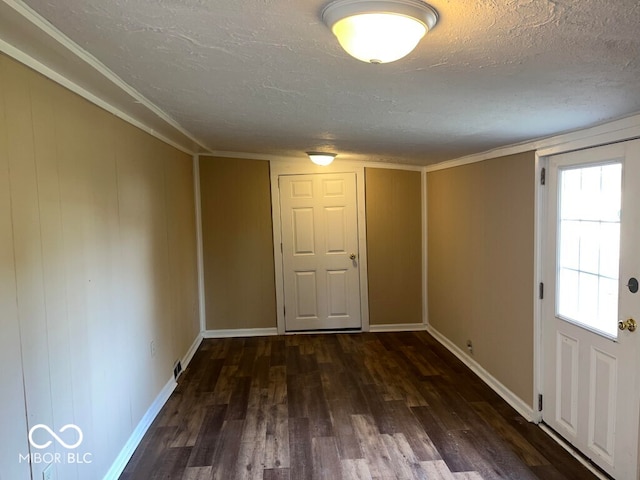 interior space featuring a textured ceiling, dark hardwood / wood-style flooring, and ornamental molding