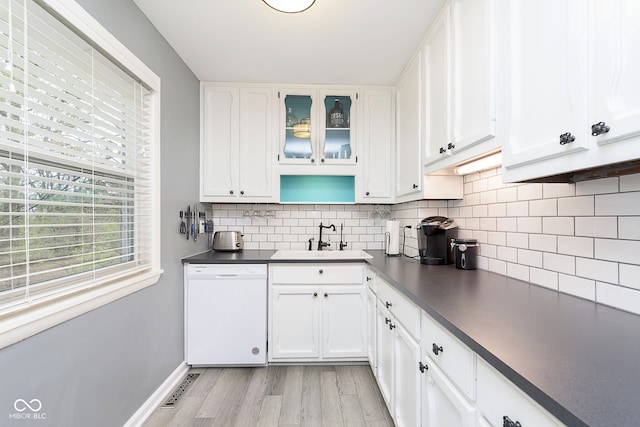 kitchen with dishwasher, backsplash, white cabinets, sink, and light hardwood / wood-style flooring