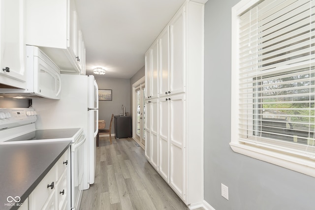 kitchen with white appliances, light hardwood / wood-style flooring, and white cabinetry