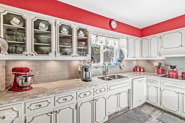 kitchen with tasteful backsplash, white cabinetry, sink, and white dishwasher