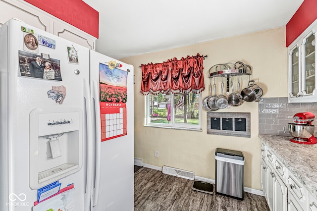 kitchen featuring decorative backsplash, light stone countertops, dark hardwood / wood-style floors, white cabinetry, and white fridge with ice dispenser