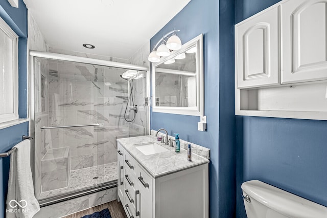 bathroom with hardwood / wood-style floors, vanity, a shower with door, and toilet