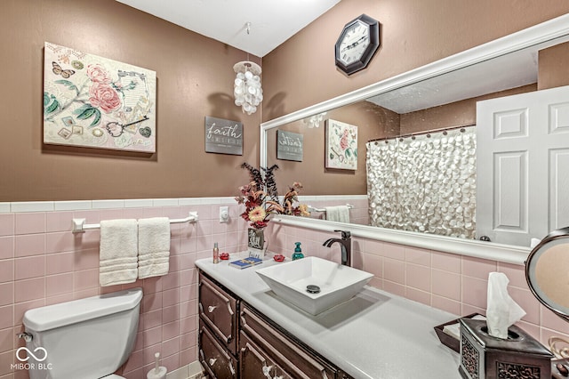 bathroom with vanity, toilet, and tile walls