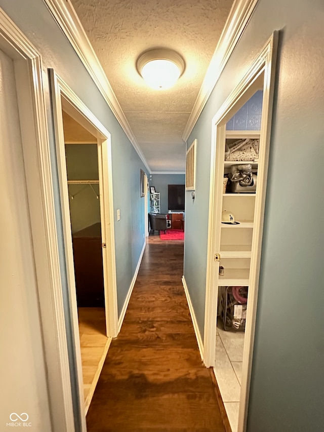 hall featuring dark wood-type flooring, a textured ceiling, and crown molding