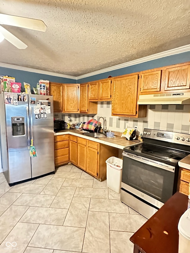 kitchen featuring light tile patterned flooring, ornamental molding, appliances with stainless steel finishes, a textured ceiling, and sink