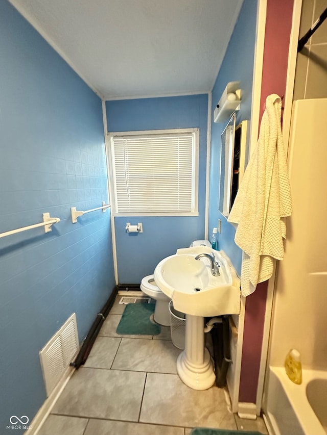 bathroom featuring toilet, washtub / shower combination, tile walls, and tile patterned floors