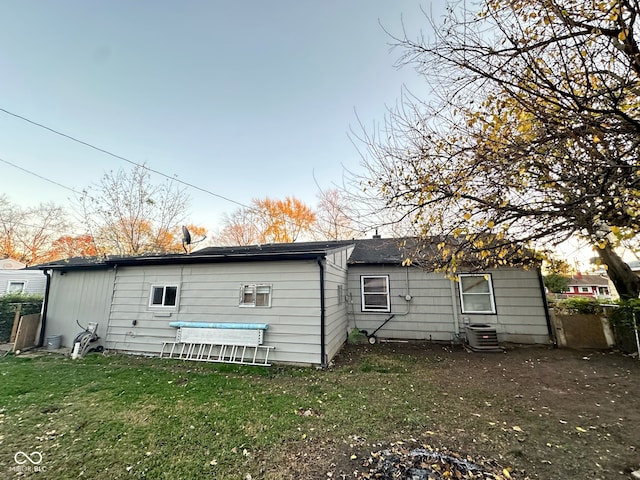 rear view of property with a lawn and cooling unit