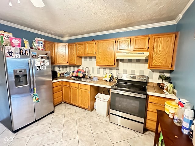 kitchen featuring stainless steel appliances, tile countertops, sink, ornamental molding, and backsplash