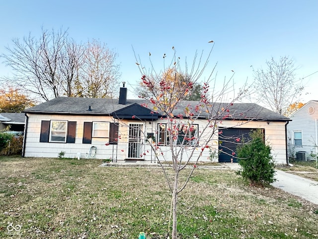 view of front of home with a front lawn, a garage, and cooling unit