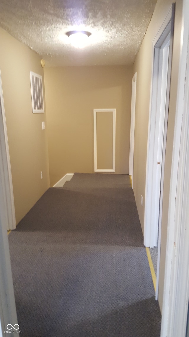 hallway with carpet flooring and a textured ceiling