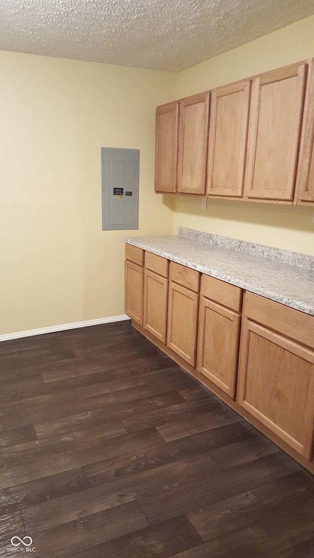 kitchen featuring a textured ceiling, dark hardwood / wood-style flooring, electric panel, and light brown cabinets