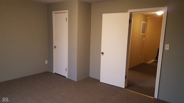 unfurnished bedroom with dark carpet and a closet