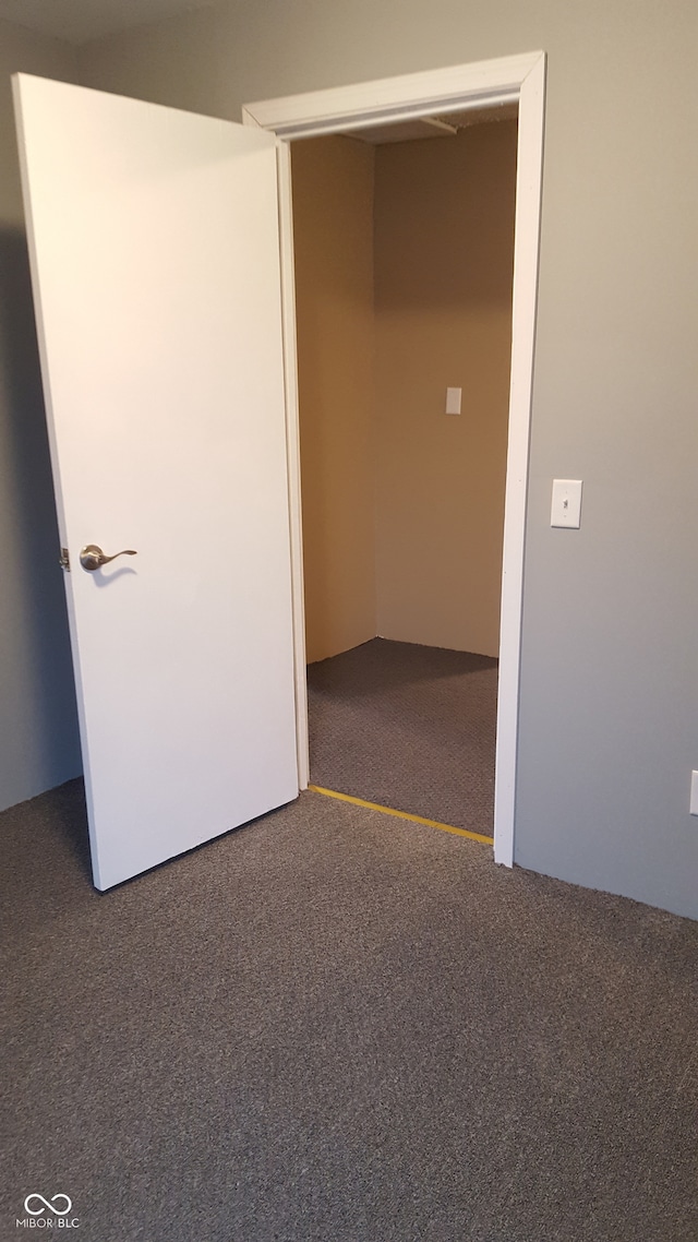 spare room with dark carpet