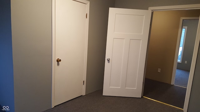 unfurnished bedroom with a closet and dark colored carpet