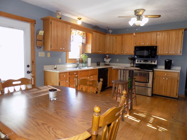 kitchen featuring black appliances, ceiling fan, light wood-type flooring, and sink