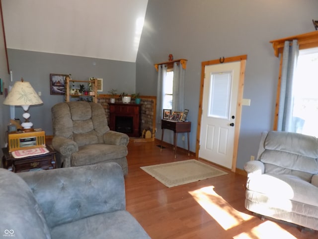 living room with hardwood / wood-style floors, a high ceiling, and a brick fireplace