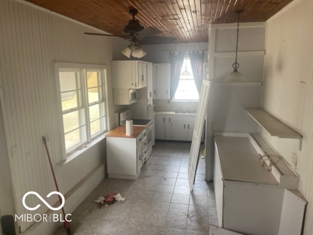 kitchen featuring wooden walls, white cabinets, white appliances, wooden ceiling, and ceiling fan