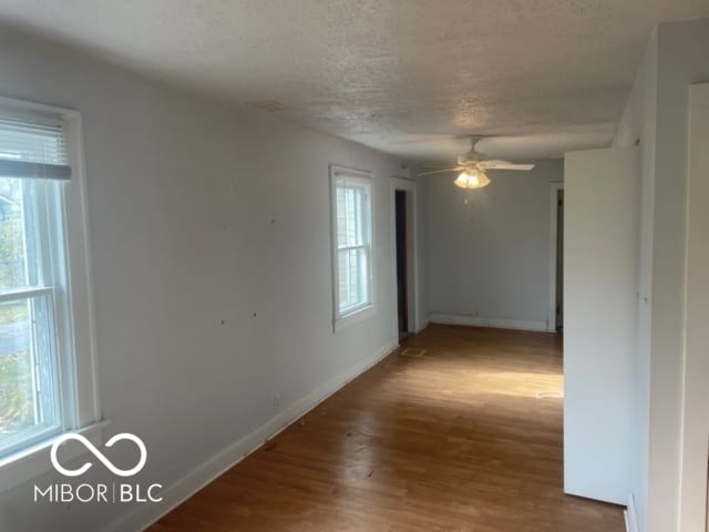 empty room with hardwood / wood-style floors, ceiling fan, and a textured ceiling