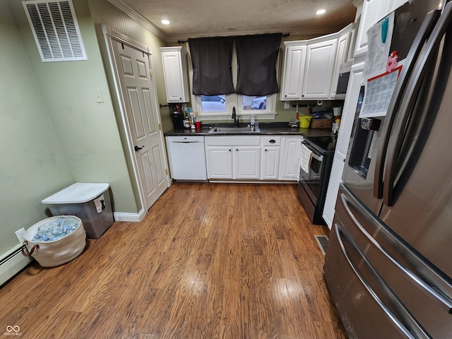 kitchen with ornamental molding, appliances with stainless steel finishes, sink, white cabinets, and dark wood-type flooring