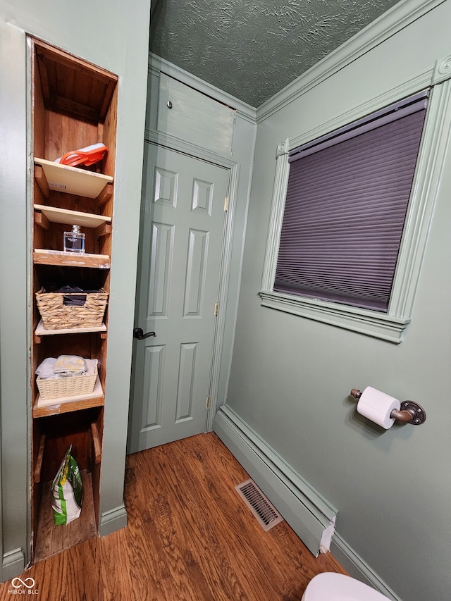 bathroom featuring hardwood / wood-style floors, a textured ceiling, and ornamental molding