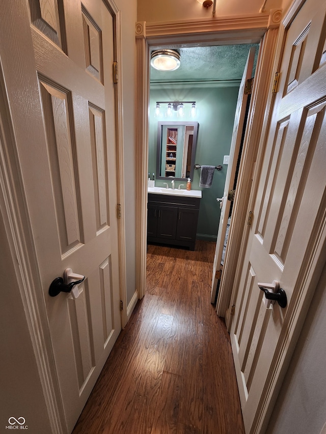 hallway with ornamental molding, a textured ceiling, dark hardwood / wood-style floors, and sink