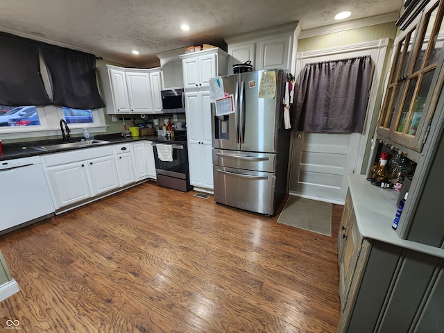 kitchen featuring stainless steel appliances, white cabinetry, a textured ceiling, sink, and dark wood-type flooring