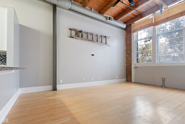 empty room with light hardwood / wood-style floors, wood ceiling, and beam ceiling