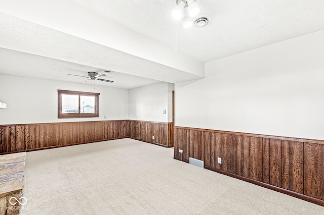 empty room with wood walls, carpet floors, and ceiling fan