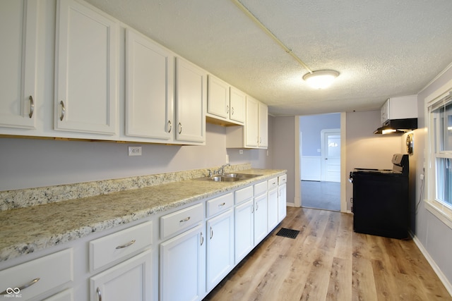 kitchen with white cabinetry, sink, black range oven, light hardwood / wood-style flooring, and a textured ceiling