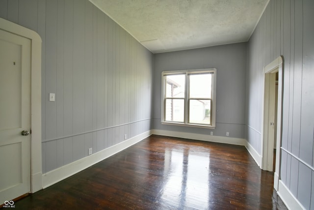 spare room featuring wood walls and dark hardwood / wood-style flooring