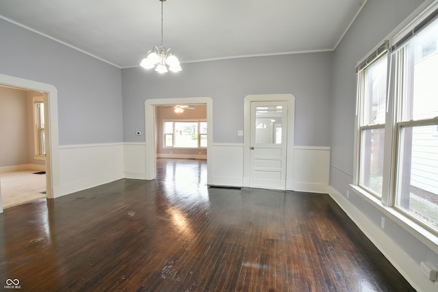 spare room featuring dark hardwood / wood-style floors, crown molding, and ceiling fan with notable chandelier