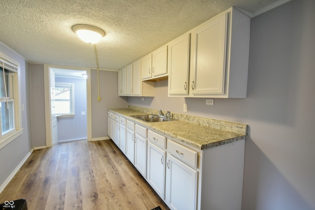 kitchen with white cabinetry, sink, a textured ceiling, and light wood-type flooring