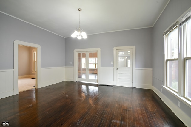 empty room with dark hardwood / wood-style flooring, ornamental molding, french doors, and a chandelier