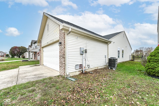 view of side of property featuring cooling unit, a garage, and a yard