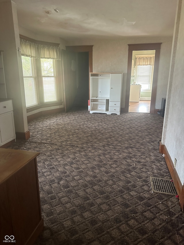 interior space featuring dark colored carpet and a healthy amount of sunlight