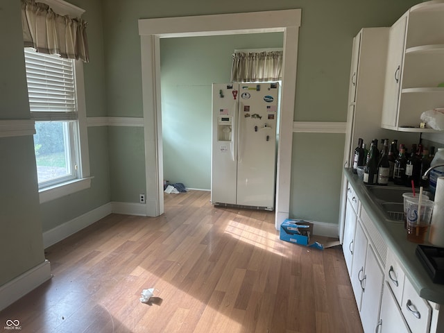 kitchen with white cabinets, white refrigerator with ice dispenser, and light wood-type flooring