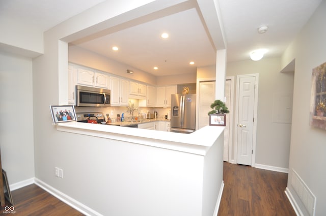 kitchen with kitchen peninsula, white cabinetry, dark hardwood / wood-style flooring, and stainless steel appliances