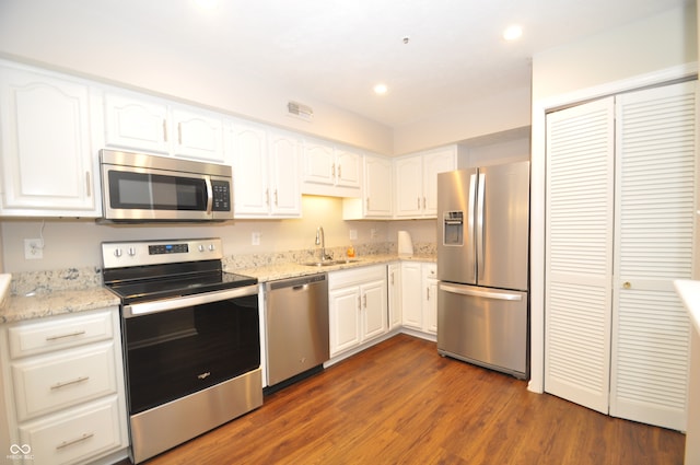 kitchen with white cabinetry, dark hardwood / wood-style flooring, light stone countertops, and appliances with stainless steel finishes