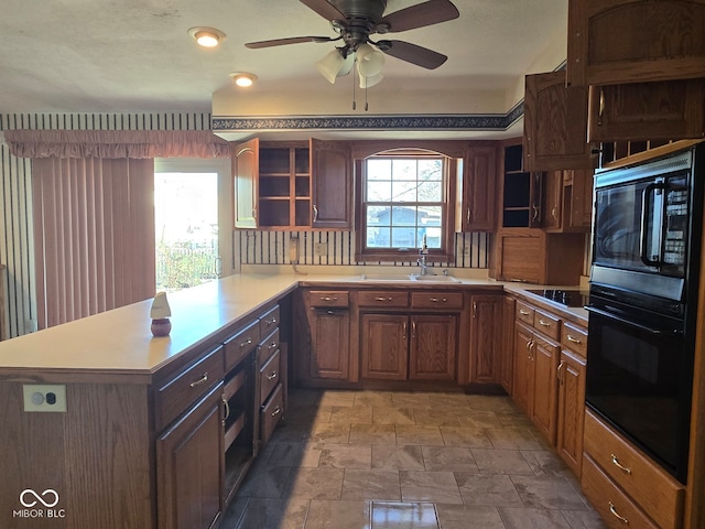 kitchen with kitchen peninsula, ceiling fan, sink, and black appliances