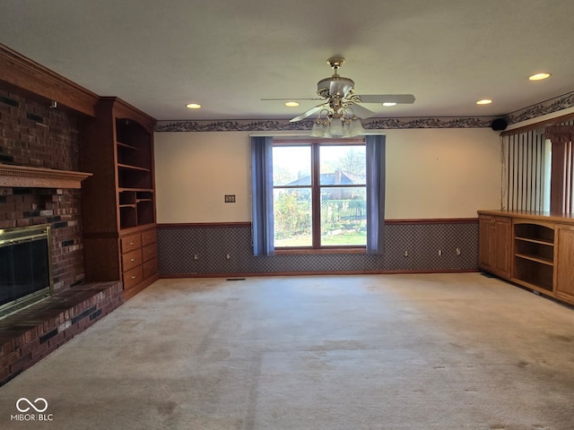 unfurnished living room with a fireplace, ceiling fan, and light carpet