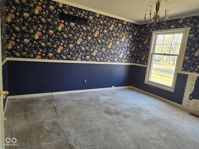 carpeted spare room with ornamental molding, a chandelier, and a textured ceiling