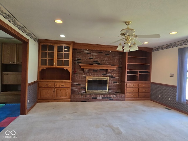 unfurnished living room featuring light carpet, a fireplace, and ceiling fan